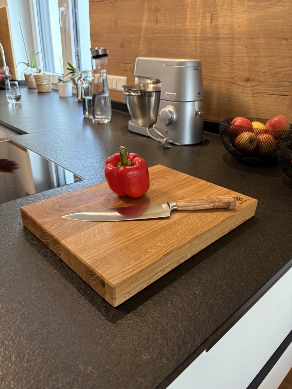 Schneidebrett Längsholz mit Kochmesser und Paprika darauf in Küche